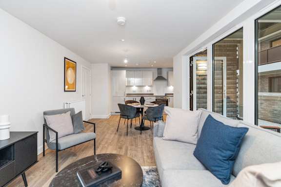 A modern living room with a grey sofa, a coffee table, and a dining table with chairs.