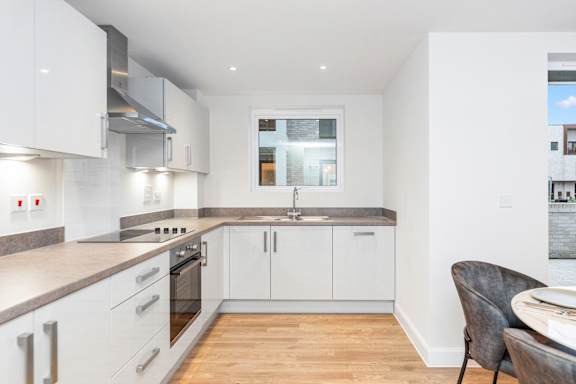 A modern kitchen with white cabinets and a wooden floor.