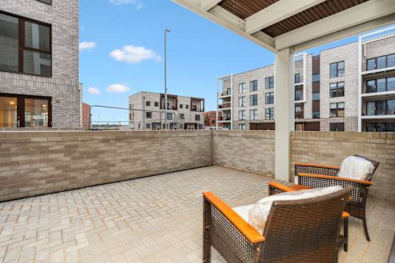 A patio with a table and chairs overlooks a courtyard with buildings.