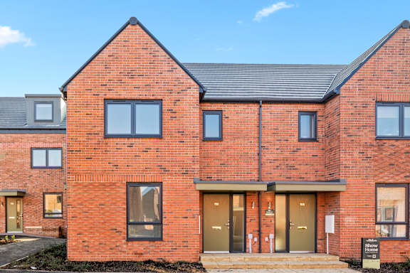 A red brick house with a black roof and a sign that says "Sale".