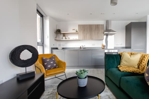 a kitchen and living room with a green couch and yellow chairs a kitchen and living room with a green couch and yellow chairs at Vox Apartments, Manchester, M15 4YD