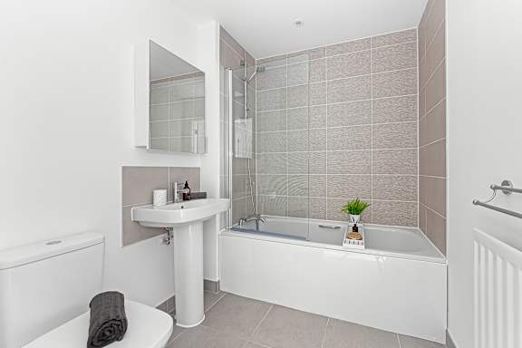 A white bathroom with a toilet, sink, and bathtub at The Woodlands Apartments, Milton Keynes