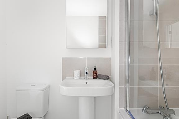 A white sink with a toilet brush and a bottle of soap on it at The Woodlands Apartments, Milton Keynes, MK5 6GS