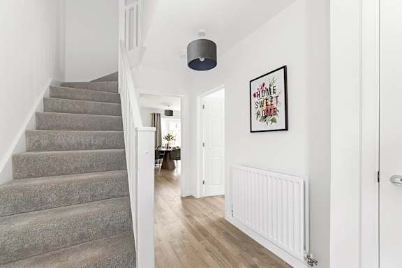 A hallway with a staircase and a framed picture on the wall at The Woodlands Apartments, Milton Keynes