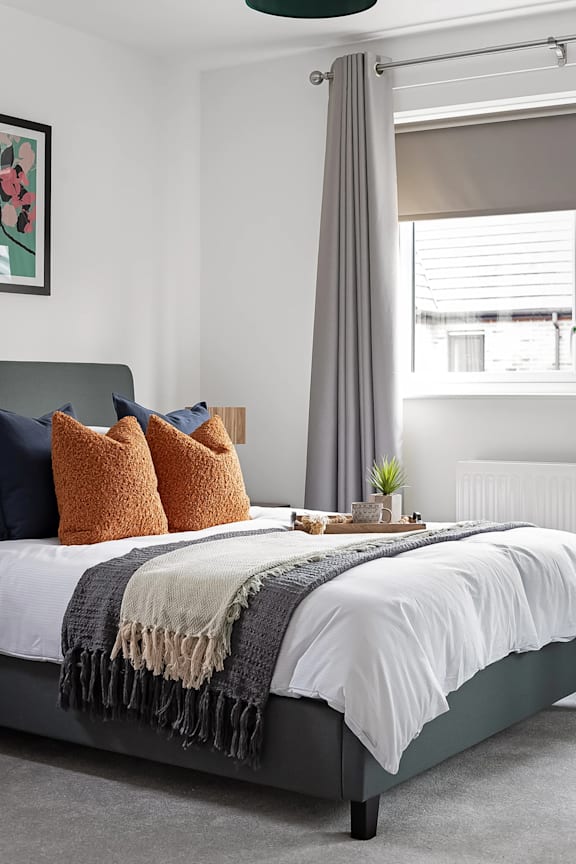 A bedroom with a bed covered in a white and grey comforter and a grey headboard at The Woodlands Apartments, Milton Keynes