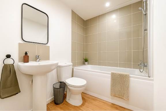 A white sink and toilet in a bathroom with a green towel hanging on the wall.