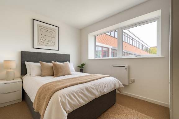A bedroom with a large bed and a window overlooking a building.