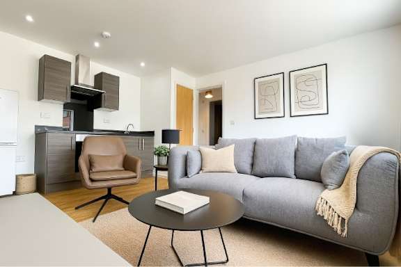 A modern living room with a grey sofa, a black coffee table, and a television.