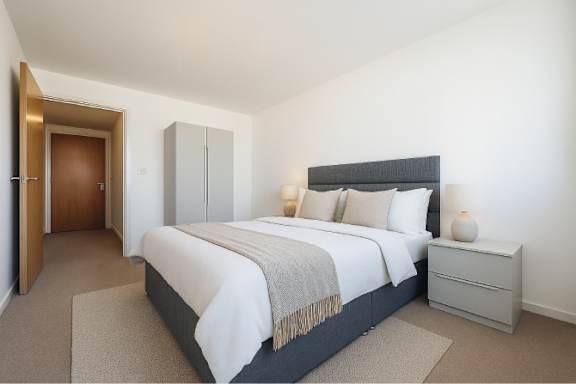 A bedroom with a large bed, a nightstand, and a wardrobe.