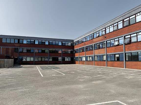 A large, empty parking lot in front of a red brick building.