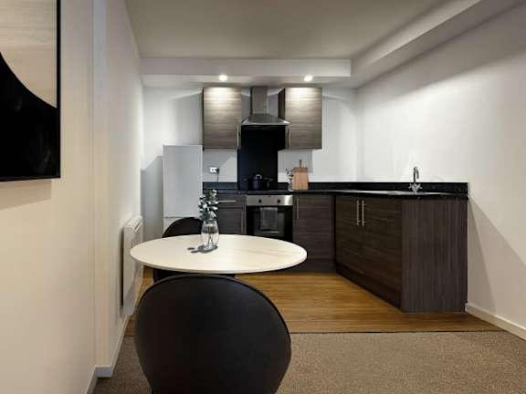 A modern kitchen with a black chair and a white table.