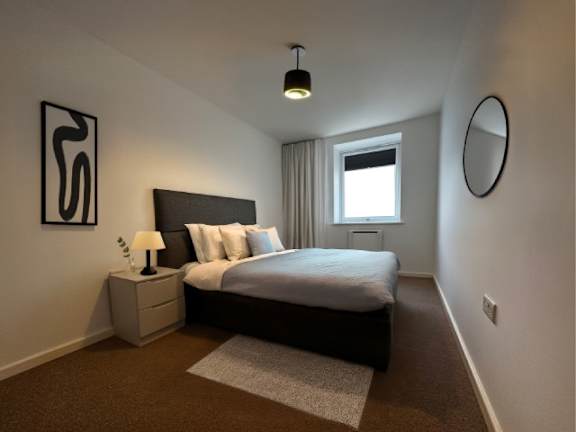 A bedroom with a bed, nightstand, and lamp.