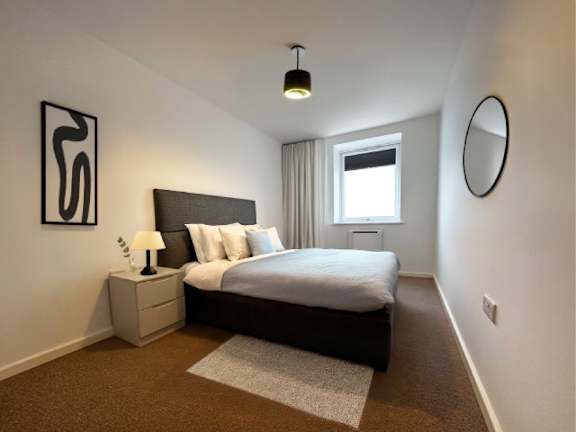 A bedroom with a bed, nightstand, and lamp.