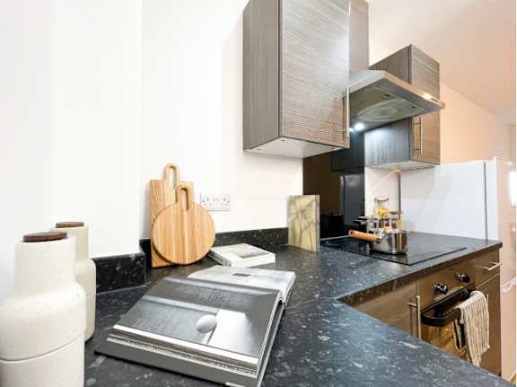 A kitchen with a black granite countertop and a white fridge.