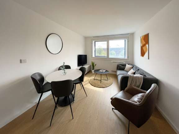 A living room with a white table and brown chairs.