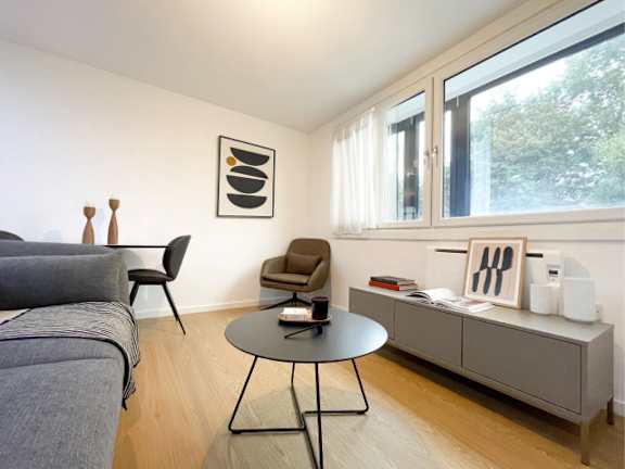 A living room with a grey couch, a black table, and a brown chair.