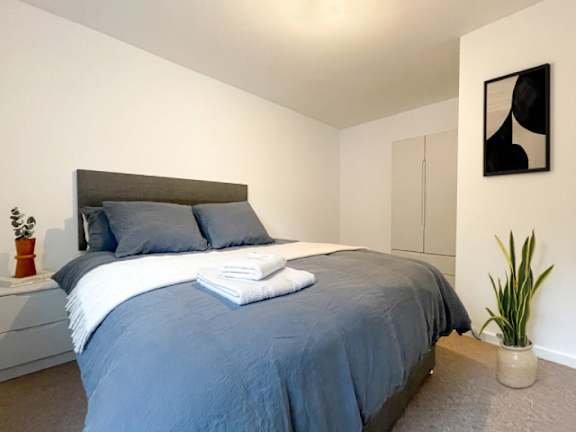 A bed with a grey comforter and a white blanket is in the image.
