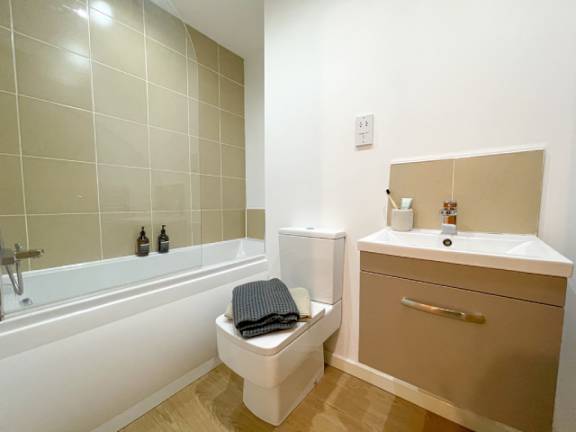 A white toilet with a black towel on top of it sits next to a bathtub in a bathroom.