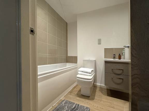 A white toilet sits in a bathroom next to a bathtub.