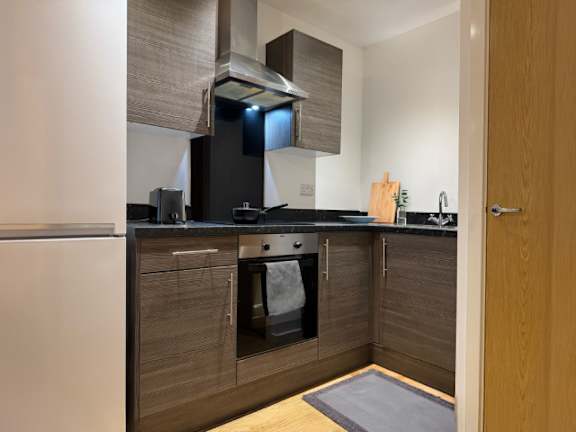 A modern kitchen with a white refrigerator and dark brown cabinets.
