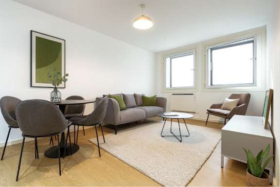 A living room with a grey couch, two chairs and a table.
