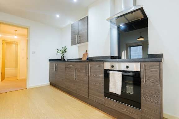 A modern kitchen with a wooden floor and dark brown cabinets.