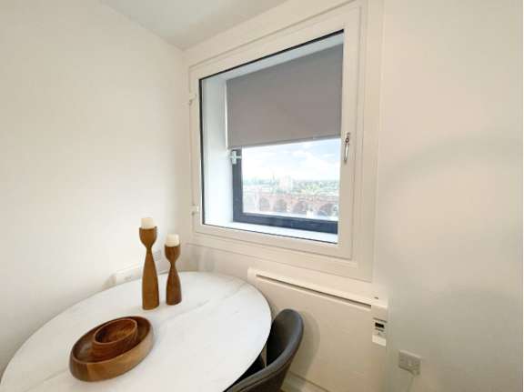 A small bedroom with a window and a bed.