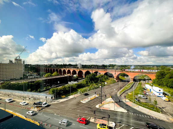 A busy city intersection with a bridge in the background.