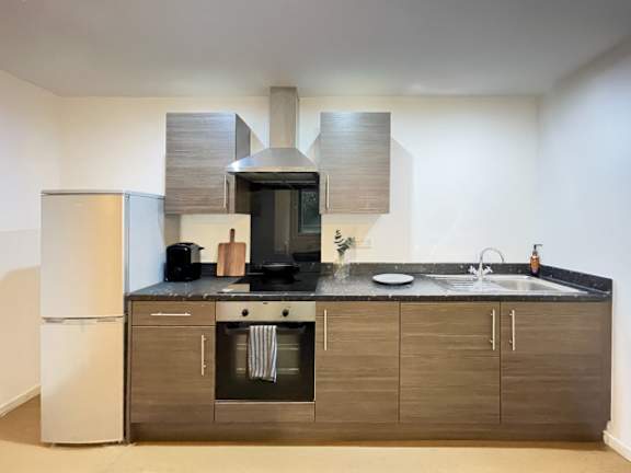 A modern kitchen with a refrigerator, oven, and sink.