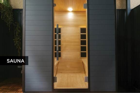 A wooden sauna with a glass door is open.