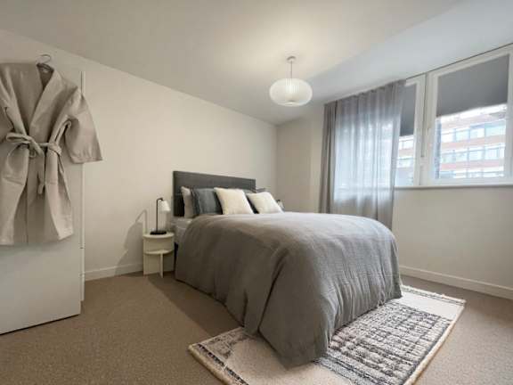 A bedroom with a large bed and a window with curtains.