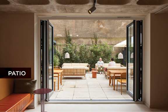 A patio with a table and chairs and two people sitting on the couch.