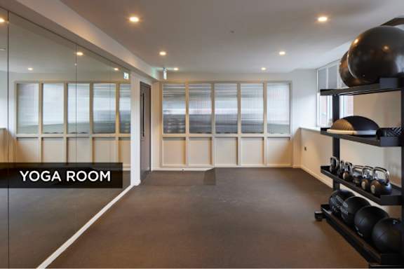 A yoga room with a mirrored wall and a shelf with weights.