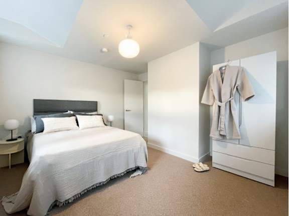A bedroom with a bed, nightstand, and a robe hanging on the door.