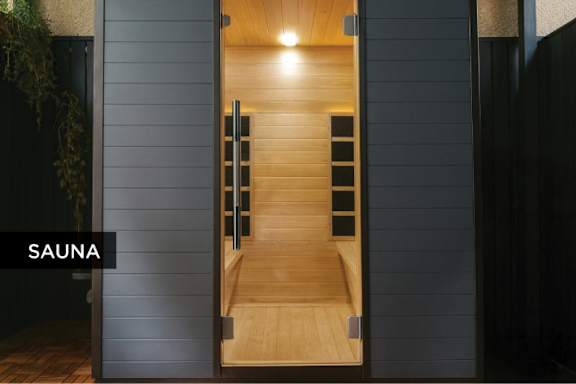 A wooden sauna with a glass door is open.