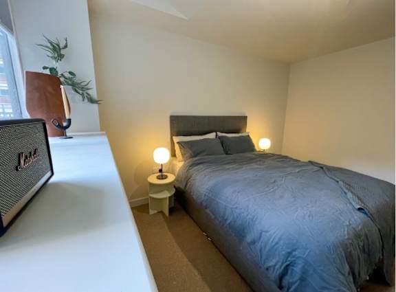 A bedroom with a bed, nightstand, and lamp.