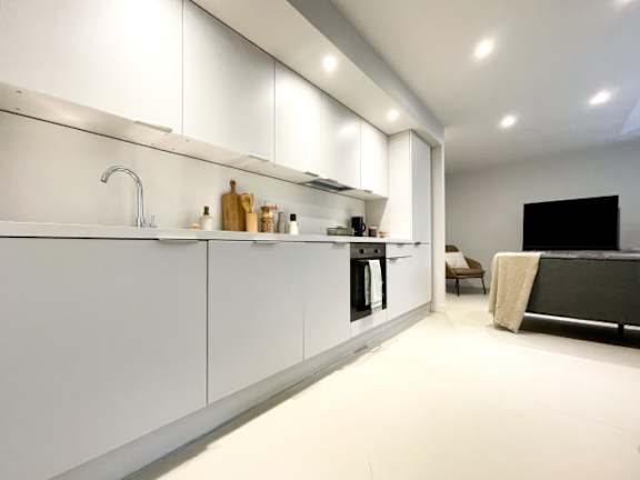 A modern kitchen with white cabinets and a black countertop.