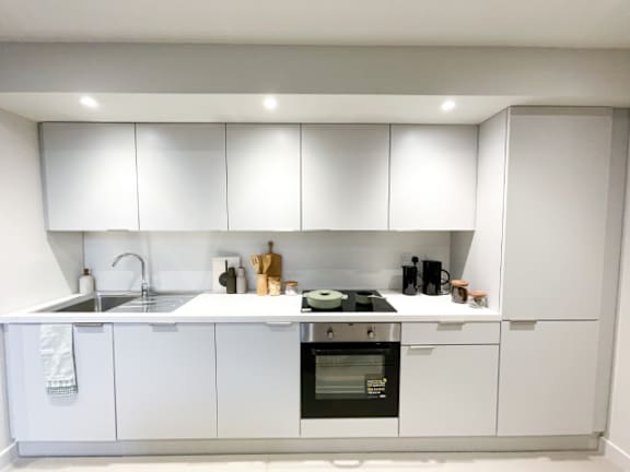 A white kitchen with a sink, stove, and cabinets.