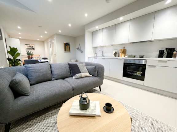 A grey couch with a wooden table in front of it.
