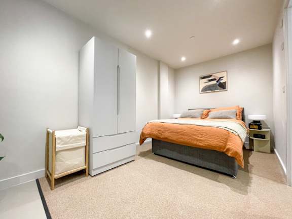 A bedroom with a bed, nightstand, and wardrobe.