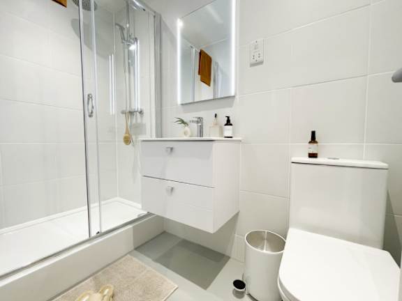 A white bathroom with a toilet, sink, and shower.
