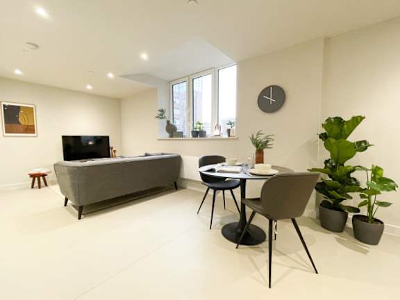 A living room with a grey sofa, a black table, and a TV.
