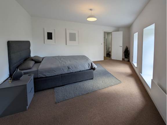 A bedroom with a bed, nightstand, and two pictures on the wall.