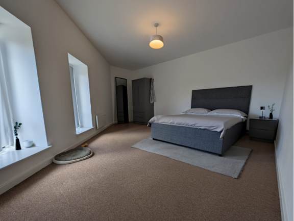 A bedroom with a bed, nightstand, and window.