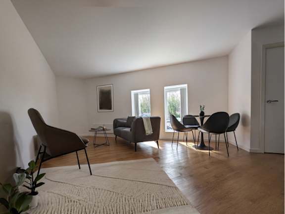 A living room with a grey sofa, two chairs and a rug.