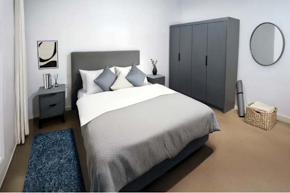 A bedroom with a large bed and a grey headboard.