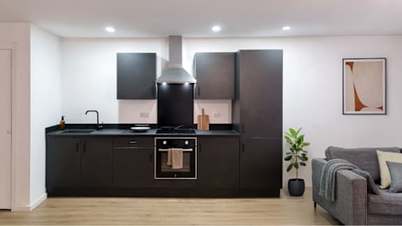 A modern kitchen with black cabinets and a stove top oven.