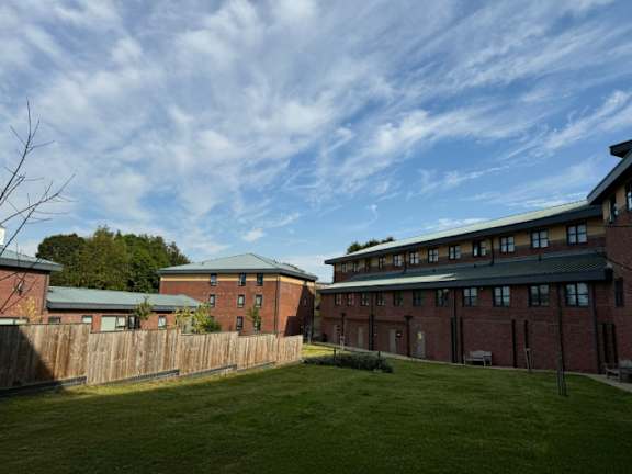 A large grassy area in front of a red brick building.