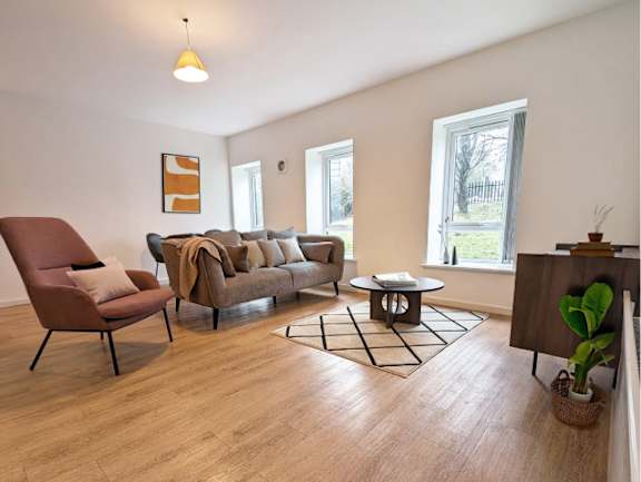 A living room with a brown chair and a grey couch.