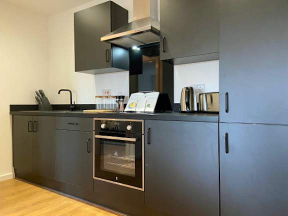 A modern kitchen with dark grey cabinets and stainless steel appliances.